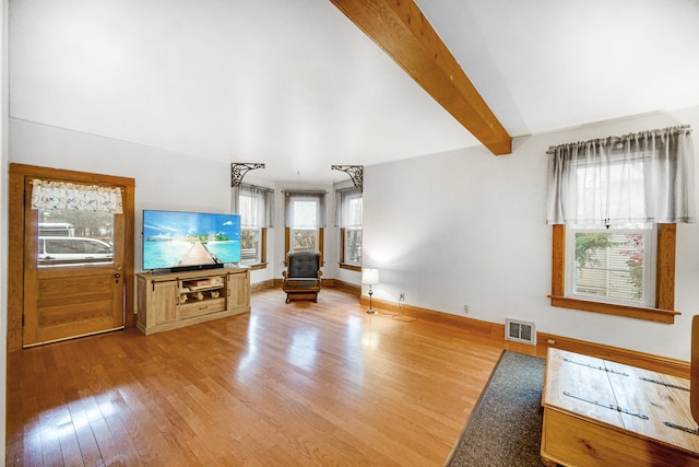 unfurnished living room featuring a wood stove, lofted ceiling with beams, and wood-type flooring