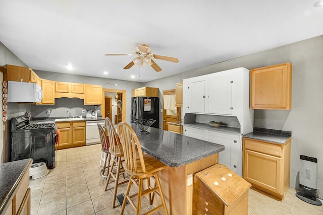 kitchen with ceiling fan, sink, black appliances, a kitchen island, and a breakfast bar area