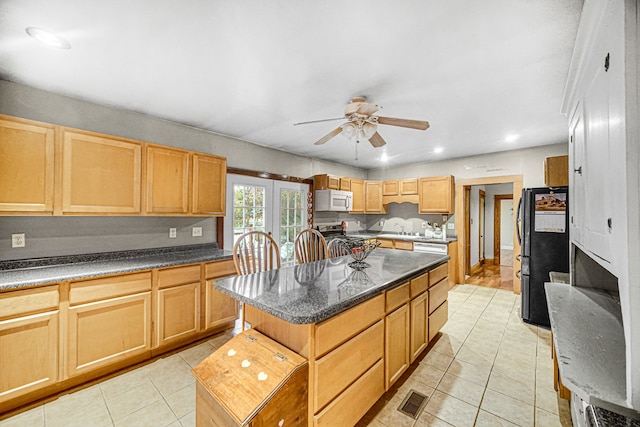 kitchen featuring light tile patterned floors, a center island, refrigerator, and ceiling fan