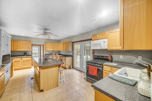 kitchen with a kitchen breakfast bar, french doors, stainless steel gas range oven, sink, and a kitchen island