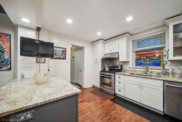 kitchen with appliances with stainless steel finishes, backsplash, dark wood-type flooring, sink, and white cabinetry