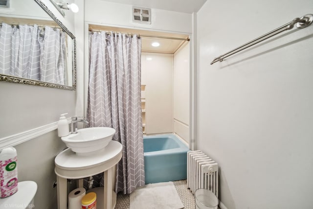 full bathroom featuring sink, shower / bathtub combination with curtain, tile patterned flooring, radiator heating unit, and toilet