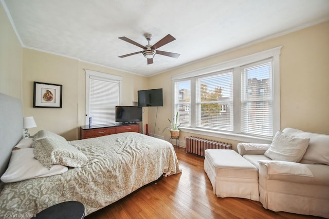 bedroom with radiator, ceiling fan, crown molding, and wood-type flooring