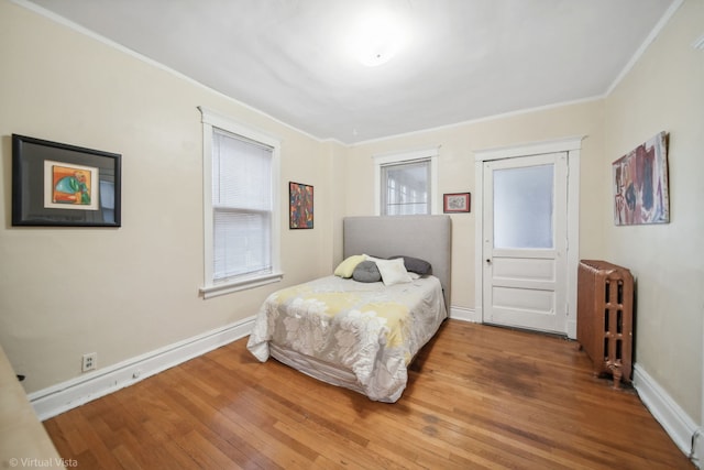 bedroom with radiator heating unit, ornamental molding, and hardwood / wood-style flooring