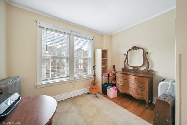 sitting room with light hardwood / wood-style floors, radiator heating unit, and crown molding