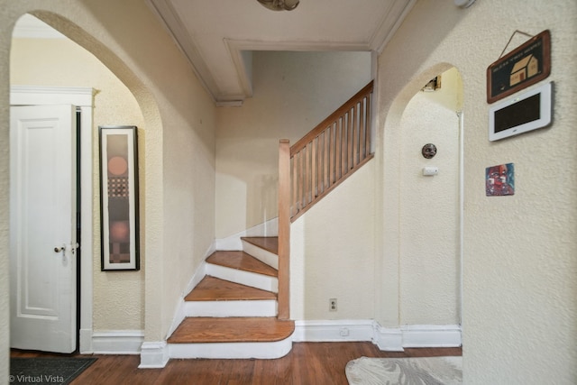 stairway with wood-type flooring and ornamental molding