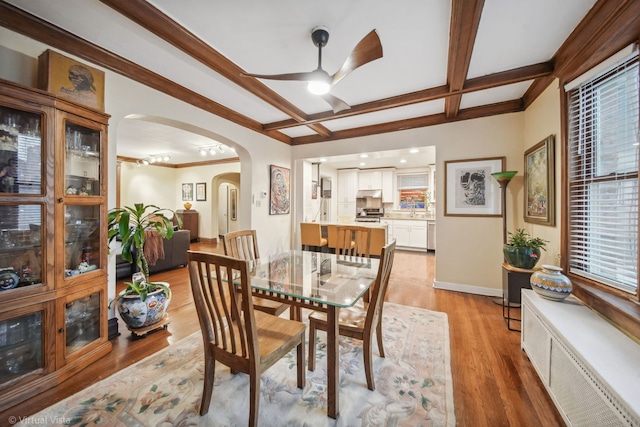 dining space with ornamental molding, coffered ceiling, ceiling fan, beam ceiling, and light hardwood / wood-style flooring