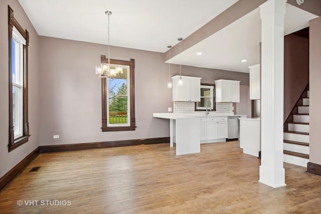 kitchen with stainless steel dishwasher, decorative backsplash, decorative light fixtures, light hardwood / wood-style floors, and white cabinetry