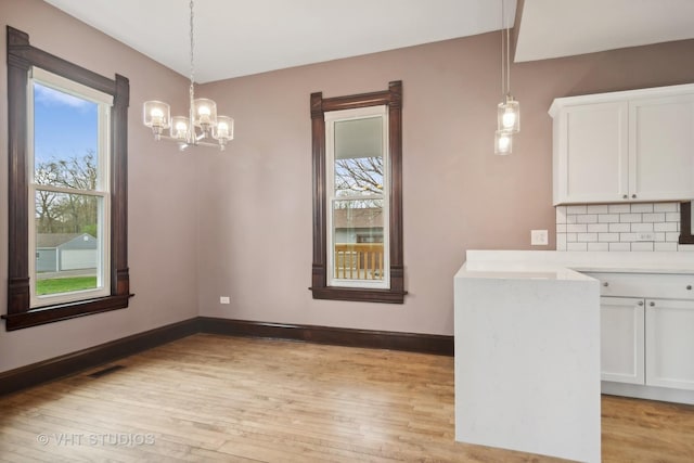 unfurnished dining area featuring a chandelier and light hardwood / wood-style flooring