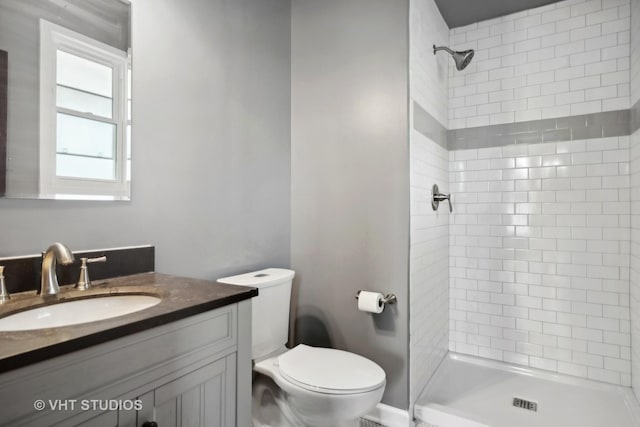 bathroom with tiled shower, vanity, and toilet