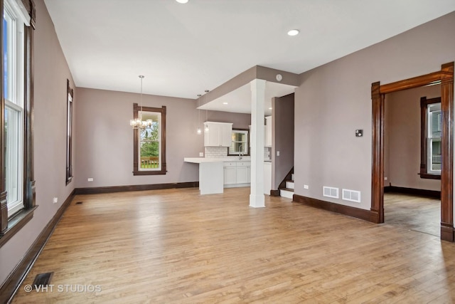 unfurnished living room with a notable chandelier and light hardwood / wood-style flooring