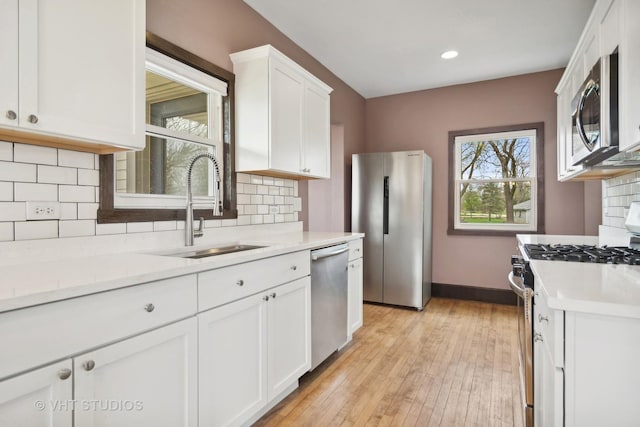 kitchen featuring appliances with stainless steel finishes, tasteful backsplash, white cabinetry, and sink