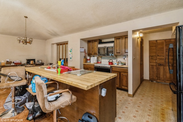 kitchen featuring a textured ceiling, black refrigerator, decorative light fixtures, and an inviting chandelier