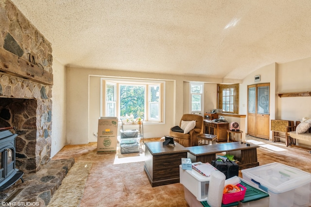 carpeted living room featuring lofted ceiling, a textured ceiling, and a wood stove