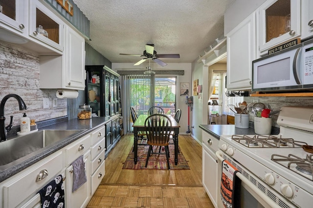 kitchen featuring white cabinetry, ceiling fan, sink, and white appliances