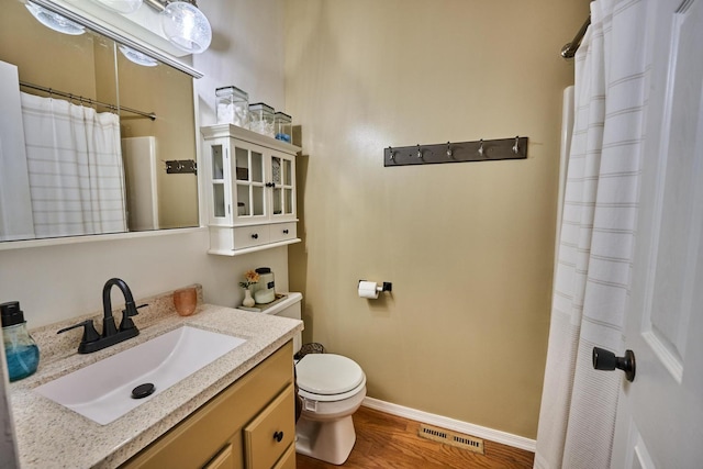 bathroom with vanity, hardwood / wood-style flooring, toilet, and walk in shower