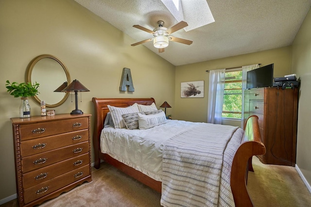 bedroom featuring vaulted ceiling with skylight, light carpet, a textured ceiling, and ceiling fan