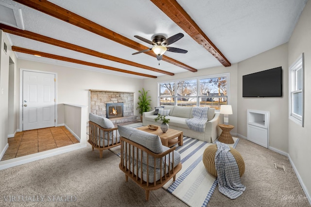 living room featuring ceiling fan, a textured ceiling, a fireplace, beam ceiling, and light colored carpet