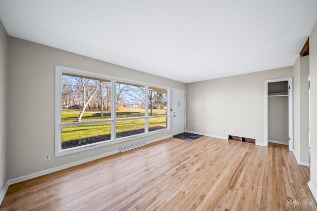 unfurnished bedroom featuring a closet, light hardwood / wood-style flooring, and multiple windows