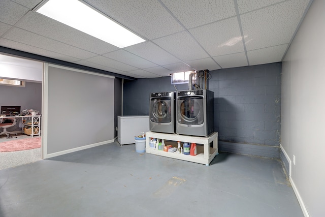 basement featuring a drop ceiling, washer and dryer, and refrigerator