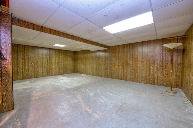 basement with a paneled ceiling and wood walls