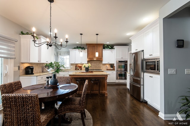 kitchen with a center island, pendant lighting, white cabinetry, appliances with stainless steel finishes, and dark hardwood / wood-style flooring