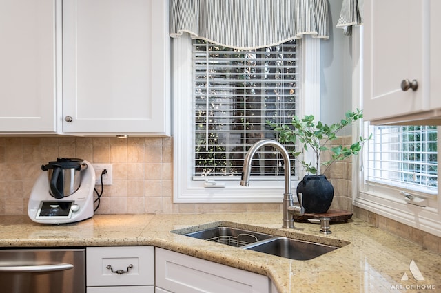 kitchen featuring white cabinetry, light stone counters, sink, and backsplash