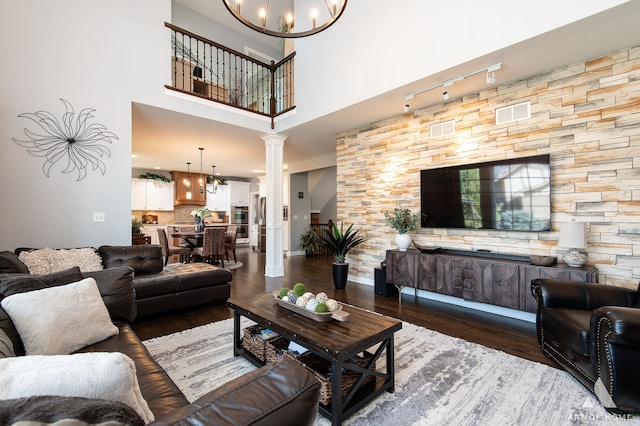 living room featuring rail lighting, ornate columns, dark hardwood / wood-style flooring, and a high ceiling