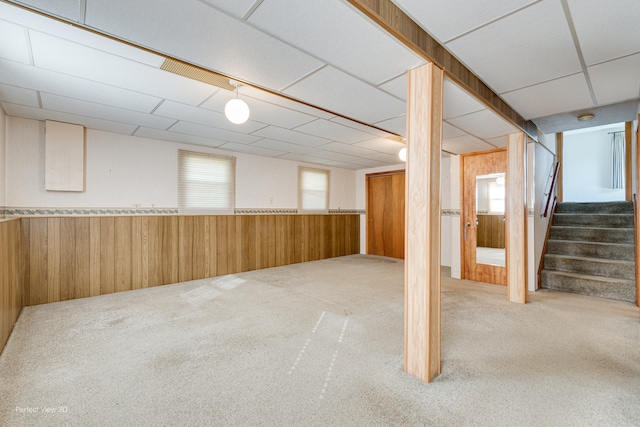 basement with plenty of natural light, wood walls, and carpet