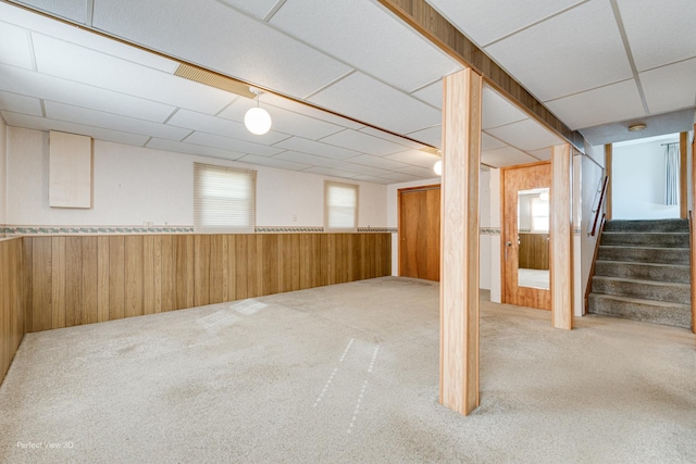 below grade area featuring stairs, a wainscoted wall, carpet flooring, and wooden walls