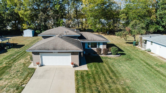 view of front of house featuring a front yard, driveway, an attached garage, and a storage unit