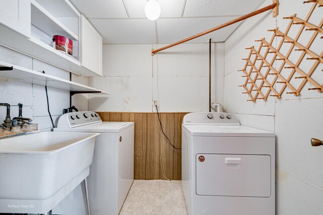 laundry area with sink, washer and clothes dryer, and wooden walls