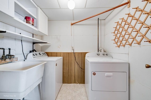 laundry area featuring laundry area, independent washer and dryer, wooden walls, and a sink