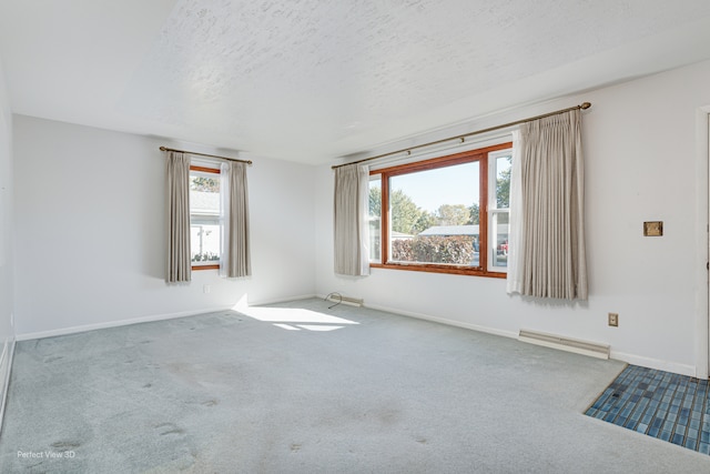 carpeted spare room with visible vents, a textured ceiling, and baseboards