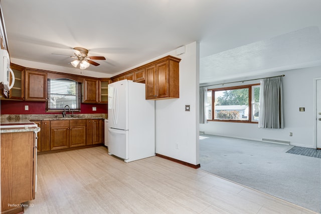 kitchen with light carpet, a baseboard radiator, ceiling fan, sink, and white appliances