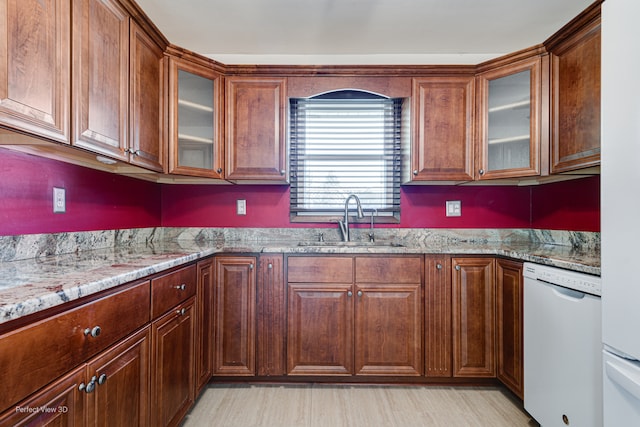 kitchen featuring light hardwood / wood-style floors, dishwasher, light stone countertops, and sink