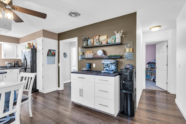 kitchen with stainless steel refrigerator with ice dispenser, a textured ceiling, dark hardwood / wood-style flooring, and white cabinets