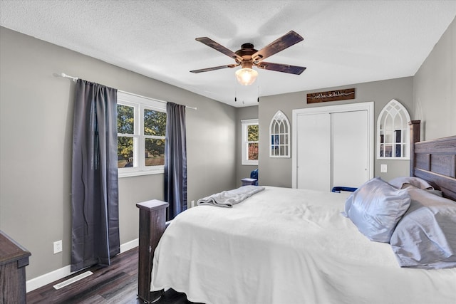 bedroom featuring dark wood-type flooring, a textured ceiling, a closet, and ceiling fan