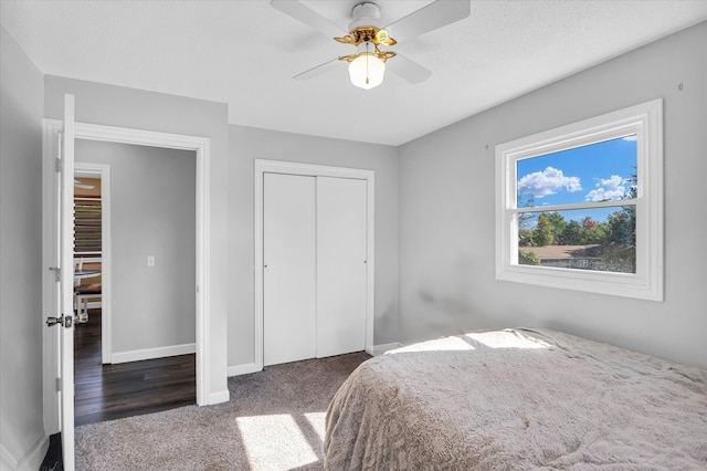 bedroom featuring dark wood-type flooring, ceiling fan, a closet, and a textured ceiling