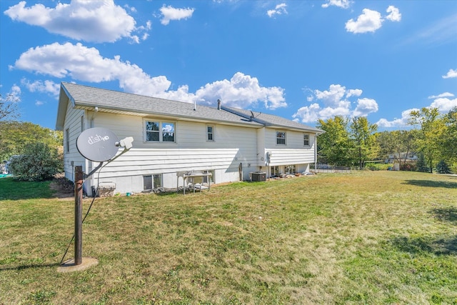 rear view of property featuring a yard and central air condition unit