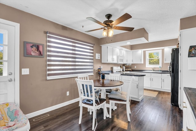 kitchen with white cabinets, ceiling fan, a textured ceiling, dark hardwood / wood-style floors, and white appliances