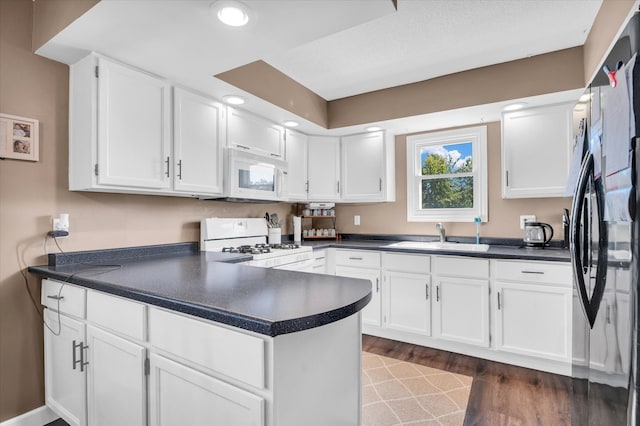 kitchen featuring kitchen peninsula, dark hardwood / wood-style flooring, white cabinetry, sink, and white appliances