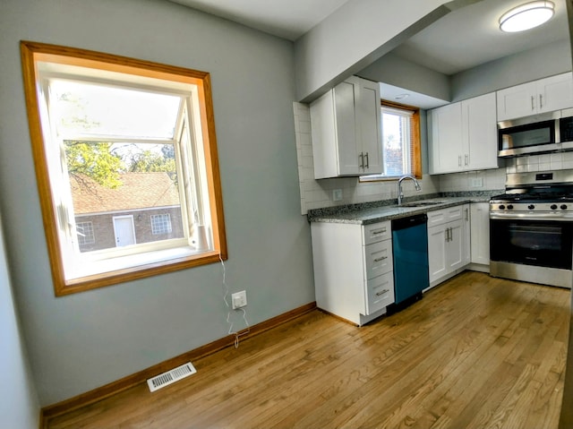 kitchen featuring stainless steel appliances, white cabinetry, a healthy amount of sunlight, and sink