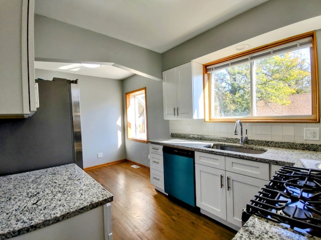 kitchen featuring sink, stainless steel appliances, backsplash, wood-type flooring, and white cabinets