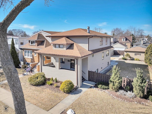 view of front facade featuring a residential view, fence, and a shingled roof