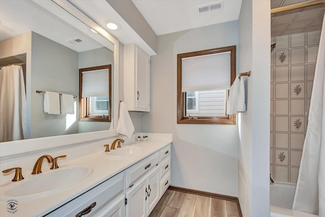 bathroom with wood finished floors, visible vents, and a sink