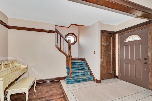 foyer entrance with baseboards, light tile patterned flooring, and stairs