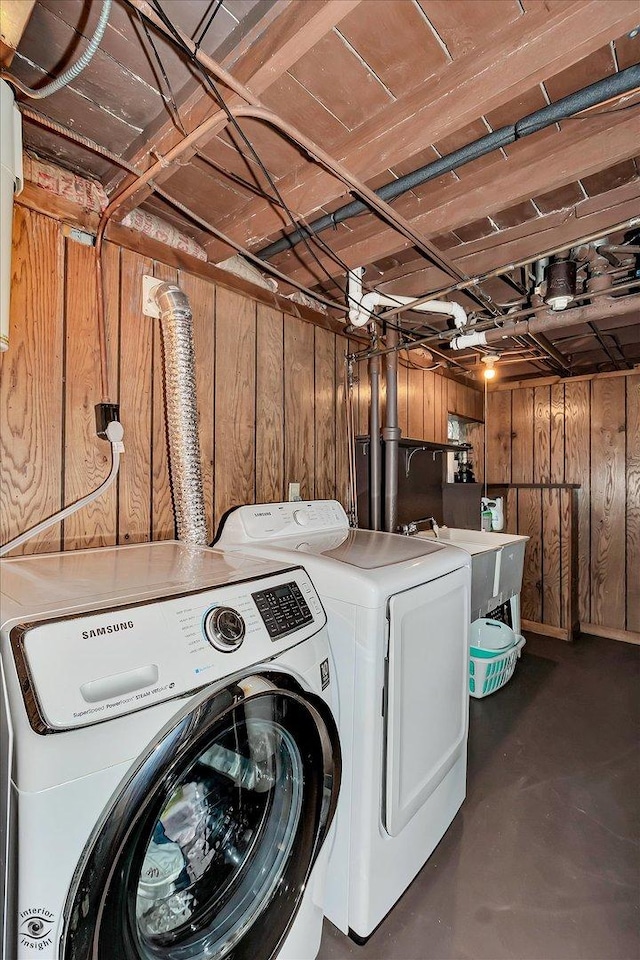 laundry area with laundry area, wooden walls, and washing machine and clothes dryer