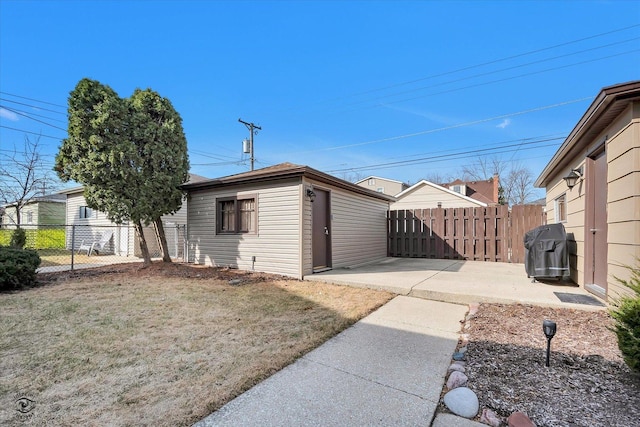 view of side of home with a patio area, fence, and a lawn