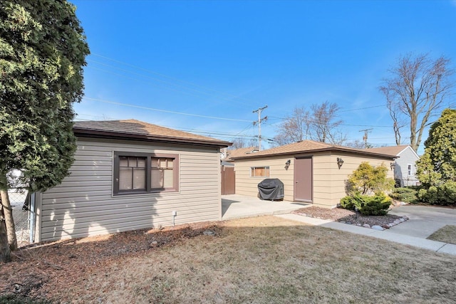 view of side of home featuring an outbuilding, a patio area, and fence